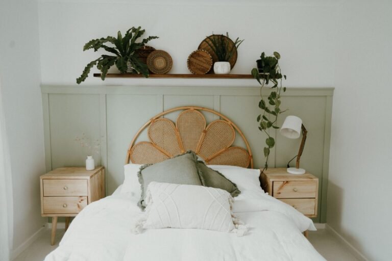 Aesthetic small bedroom with a woven rattan headboard, sage green pillows and a shelf of plants above the bed