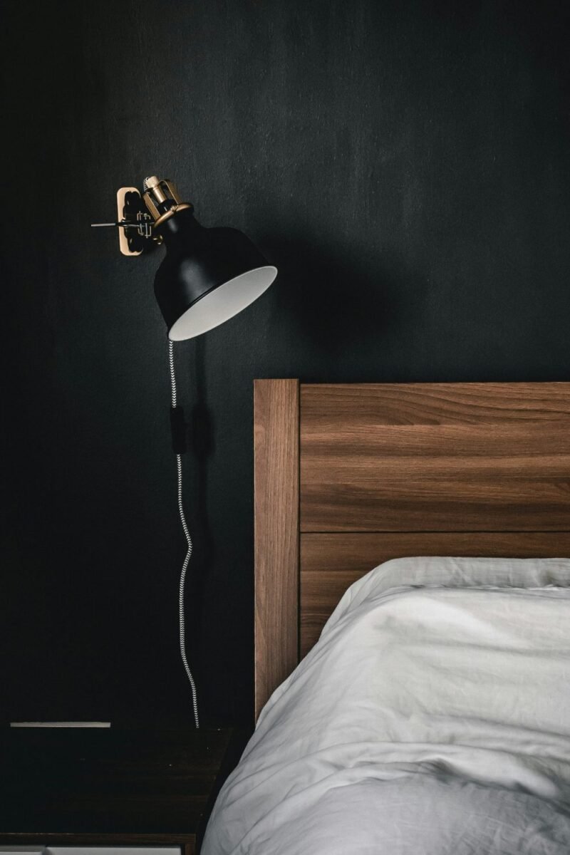 Small teen bedroom with a moody dark accent wall and a warm wall lamp