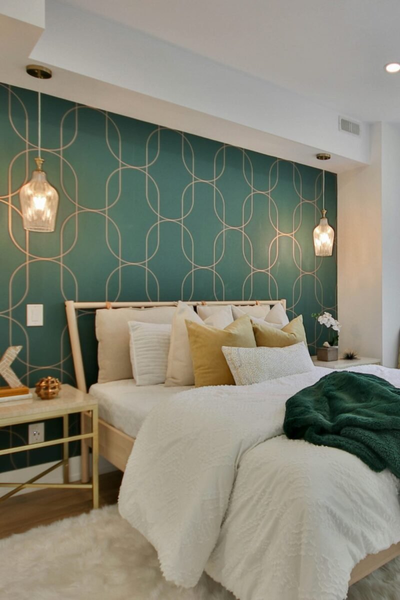Small bedroom for a couple with a green accent wall and warm pendant lights on each side of the bed