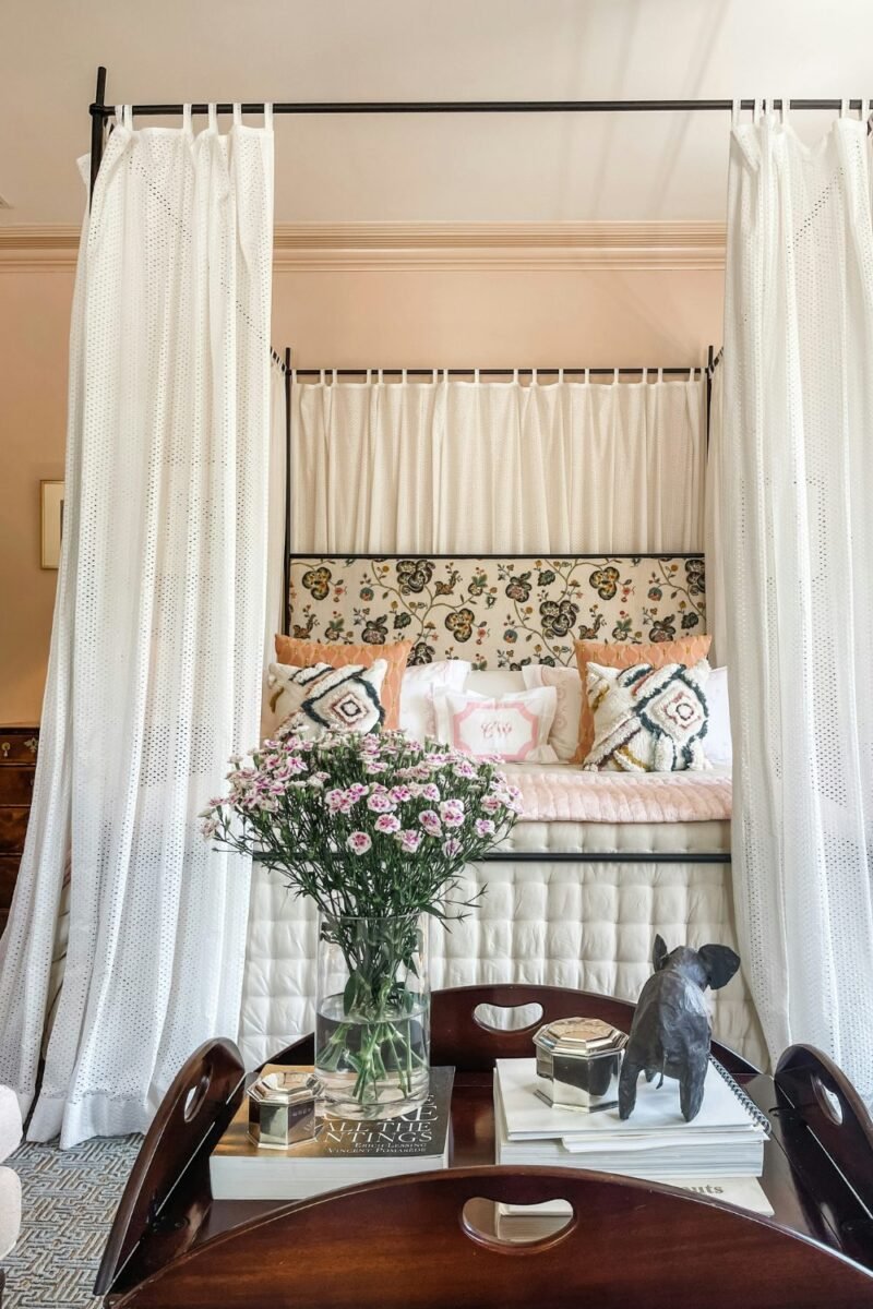 Small bedroom bed framed by a soft fabric canopy with layered bedding