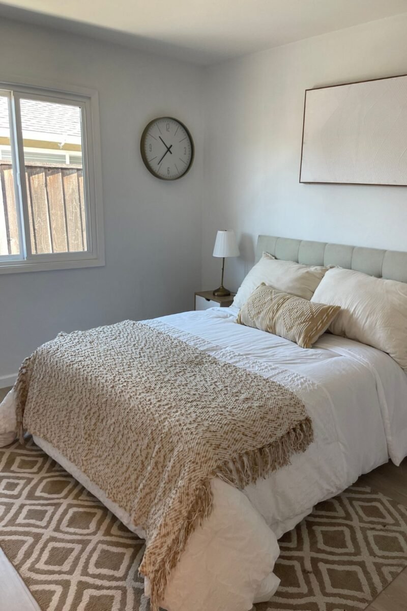 Cozy small bedroom bed layered with a chunky knit throw, framed art and a patterned rug