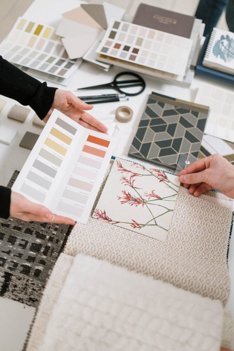 Hands arranging paint swatches and fabric samples for a small bedroom makeover
