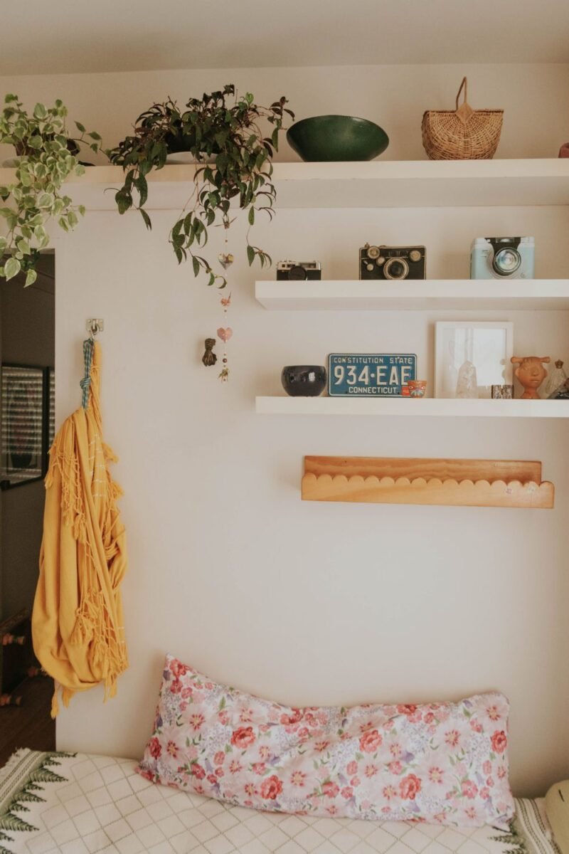 Floating wall shelves and hooks used for vertical storage in a small bedroom