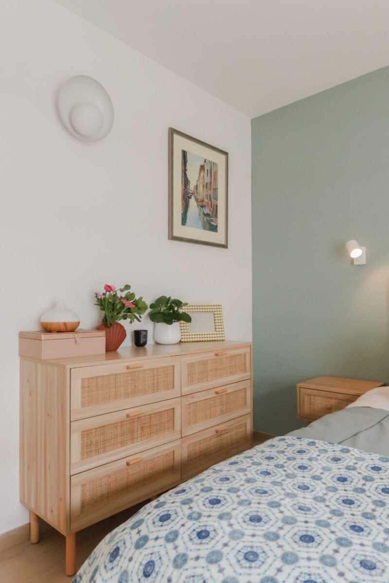 One shared wooden dresser topped with plants in a small bedroom for two