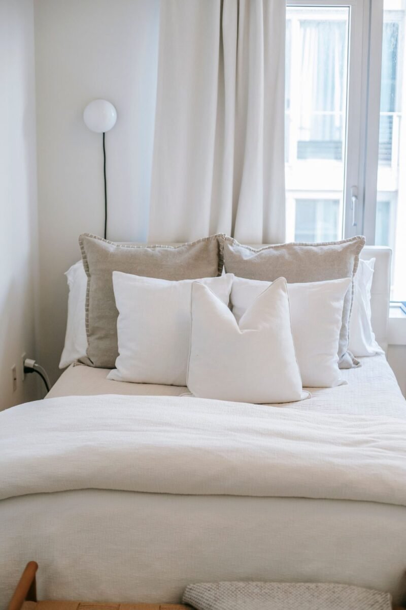 Neatly made small guest bed with crisp white linens and layered pillows