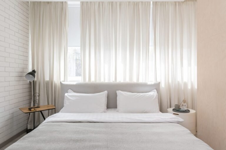 Cozy small guest bedroom with soft neutral bedding and natural light
