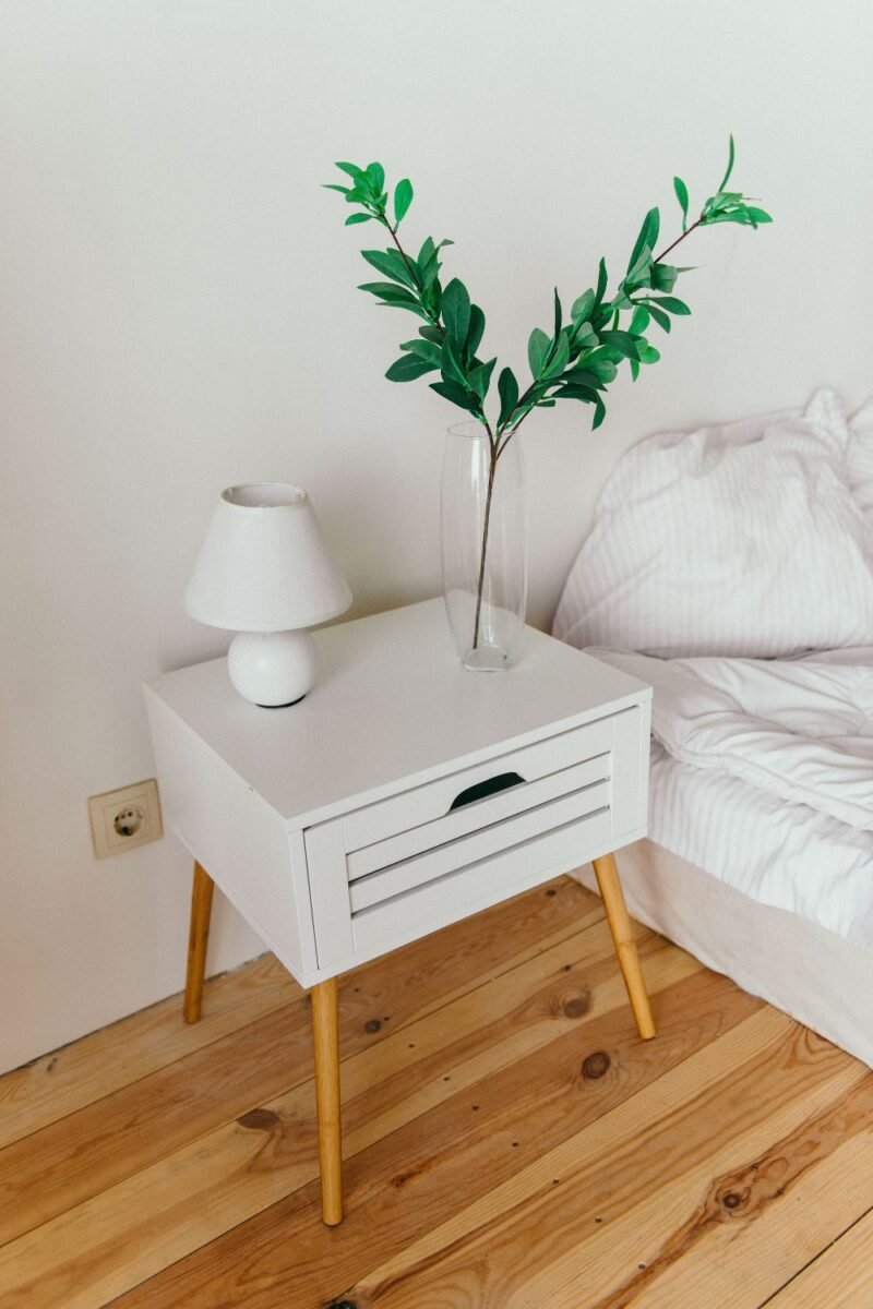 Bedside nightstand with a lamp and simple decor in a small guest room