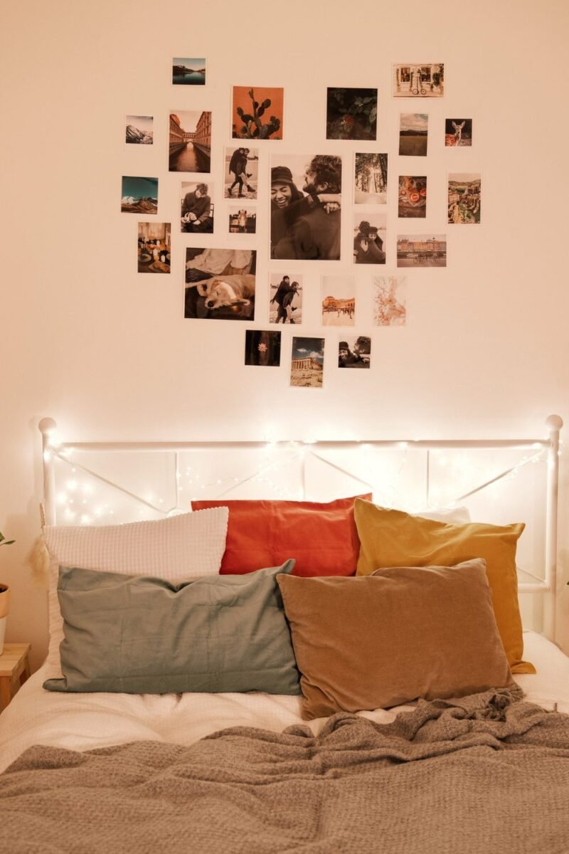 Heart-shaped photo collage and warm string lights above a bed in a small teen bedroom