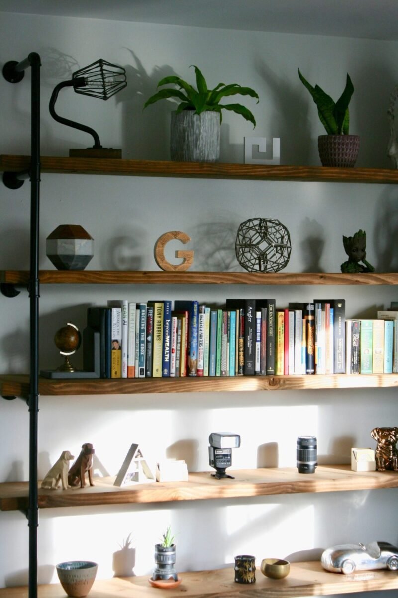 Open wall shelves holding books, plants and small decor in a teen bedroom