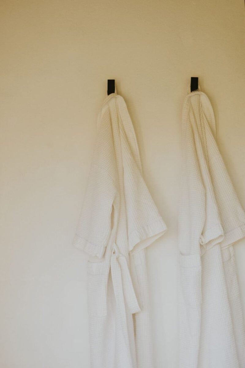 Two robes hanging on wall hooks to save floor space